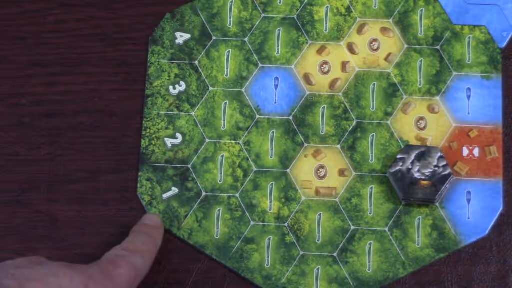 Hand pointing at The Quest for El Dorado game board with hexagonal terrain tiles and tokens.