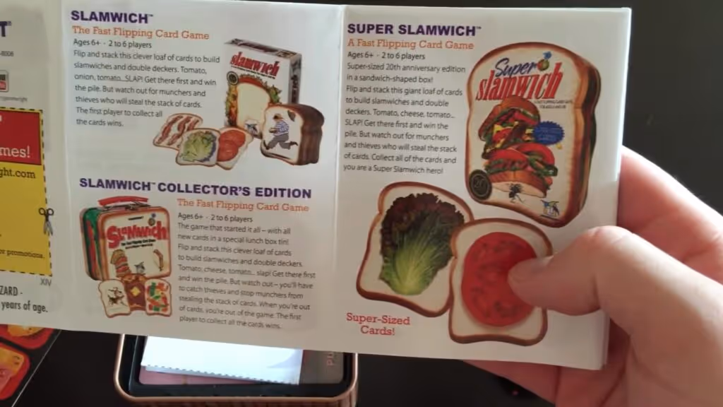 Hands holding the Sushi Go card game rules of play and tin box on a table.