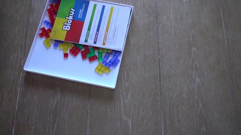 Blokus game box with colorful red, blue, green, and yellow pieces spilling out onto a wooden surface