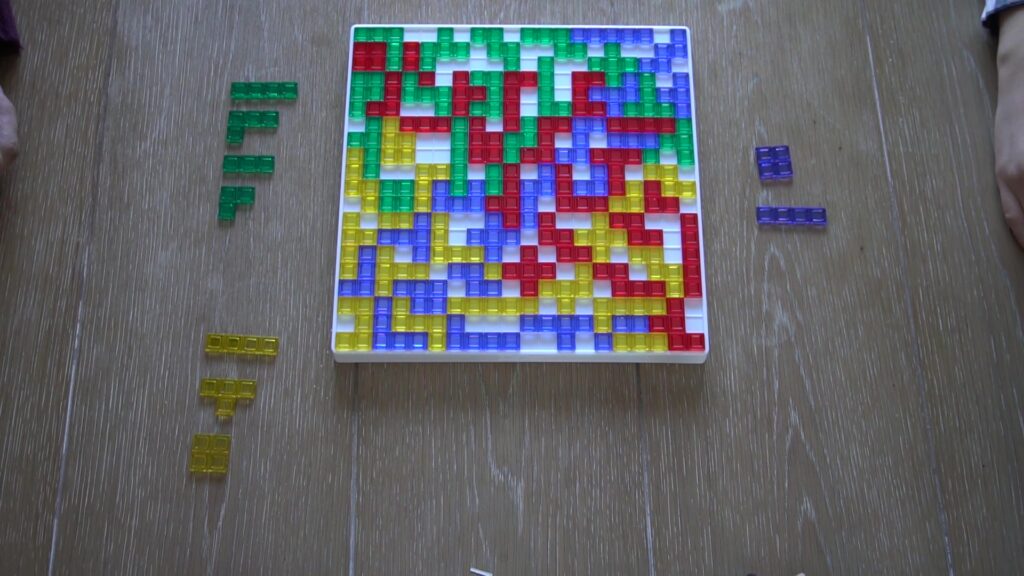 Blokus board game with green, purple, red, and yellow pieces almost filling the board.