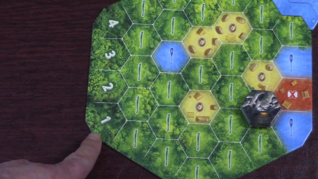 Hand pointing at The Quest for El Dorado game board with hexagonal terrain tiles and tokens.