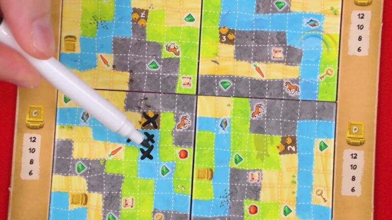 Hand pointing at a game board with various terrain tiles and tokens.