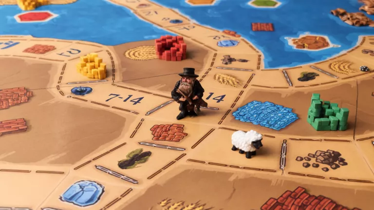 Catan game board with robber and resource cards.