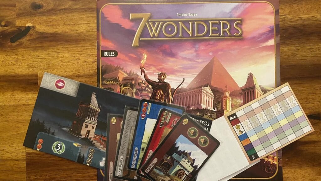 7 Wonders board game box, Wonder boards, resource cards, and score sheet displayed on a wooden table.
