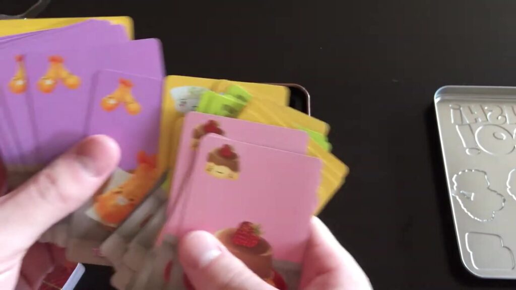 Hands holding Sushi Go! cards with various sushi dishes and colors